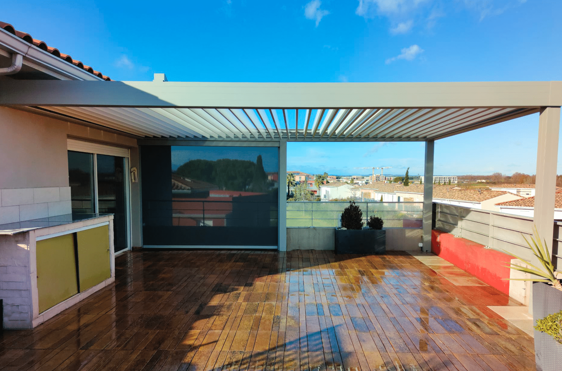 Pergola Bioclimatique aluminium gris anthracite sur terrasse en bois.